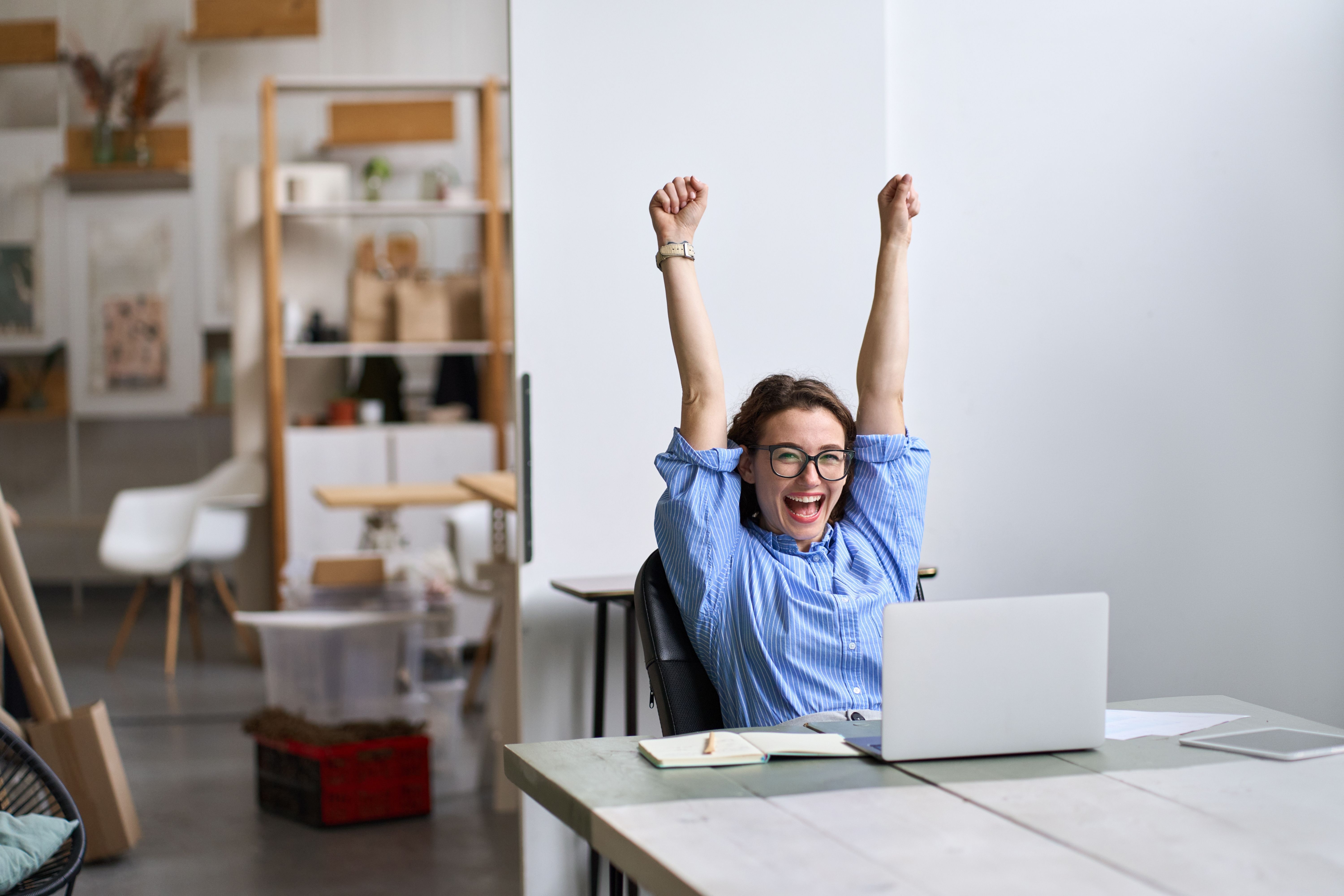 Woman sitting in front of computer with gesture of victory