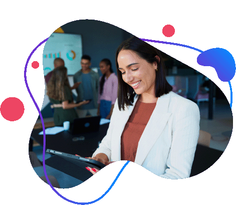 Smiling businesswoman using a tablet in a modern office with colleagues collaborating in the background.