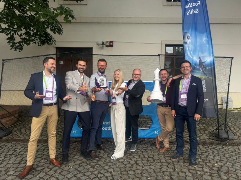 Group of seven smiling professionals posing outdoors with an Unchain Innovation Excellence Award and a giant white chess piece.