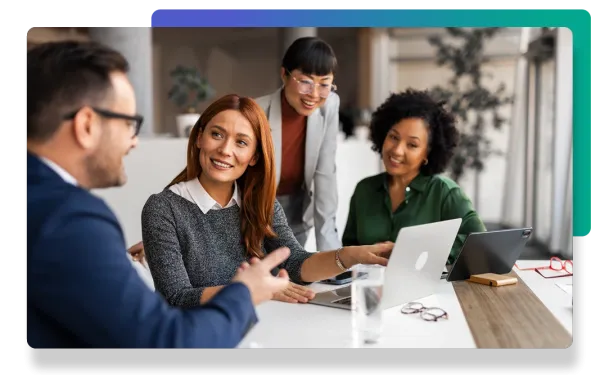 Group of diverse professionals collaborating around a laptop in a modern office environment.