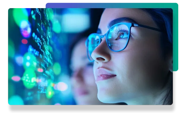 Close-up of a woman in glasses looking at data analysis screens displaying green graphs and code.