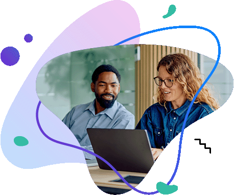 Two colleagues collaborating and smiling while looking at&nbsp;a&nbsp;laptop screen in&nbsp;a&nbsp;bright office.