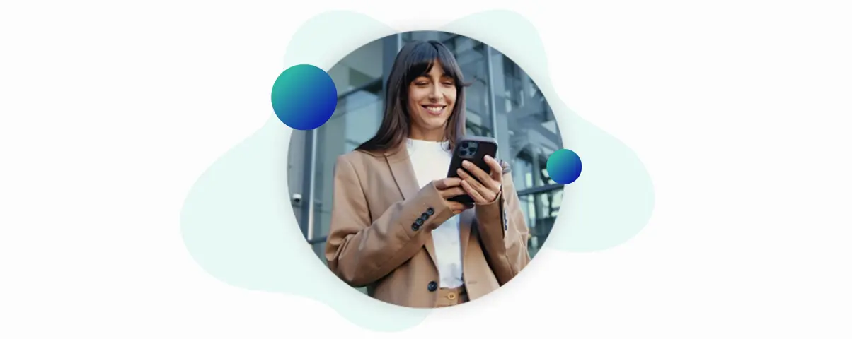 Smiling businesswoman using a smartphone outdoors in front of a modern glass building.
