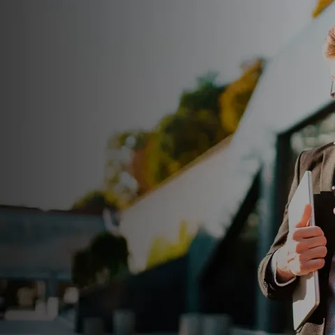 Man in a suit smiling while using a smartphone on a busy city street with cars in the backgroun