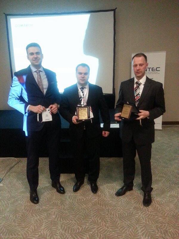 Three men in&nbsp;formal attire holding awards stand in&nbsp;front of&nbsp;a&nbsp;presentation backdrop at&nbsp;an&nbsp;event.